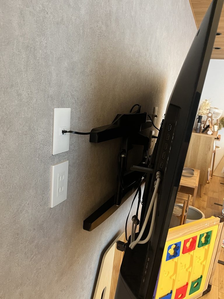 壁からテレビを手前に引き出した状態。テレビ背面に、角度調整ができる可動式の壁掛け金具と配線が見える。