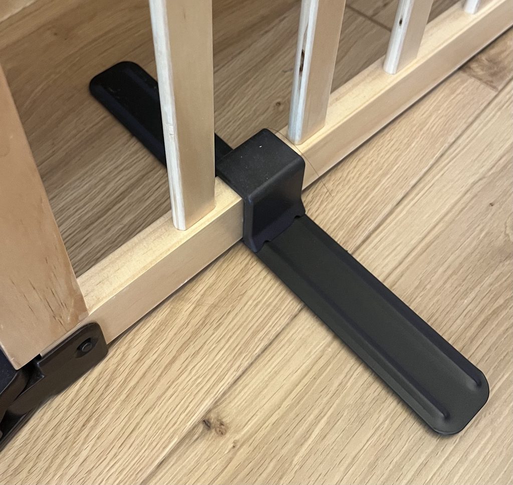 木製パーテーションの下部に取り付けられた、床に長く伸びる黒い転倒防止用の脚。