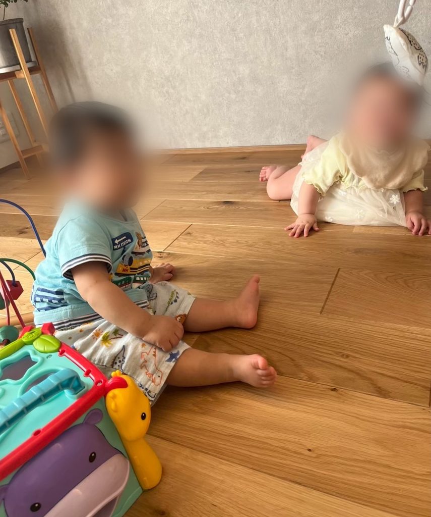 挽板フローリングのリビングで床に座って遊ぶ子どもたち
